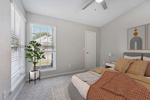 a bedroom with a bed and two windows and a ceiling fan