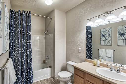 A bathroom with a white toilet, a white sink, and a blue shower curtain.