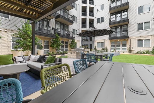 a patio with a table and chairs in front of an apartment building