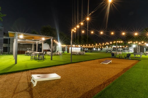 a night view of a yard with tables and chairs and lights