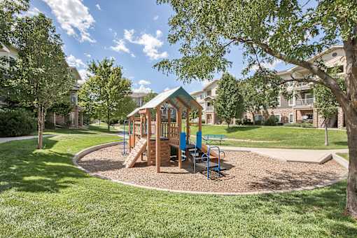 A playground with a wooden swing set and blue chairs.