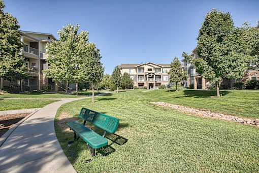 A park with a bench and apartment buildings in the background.