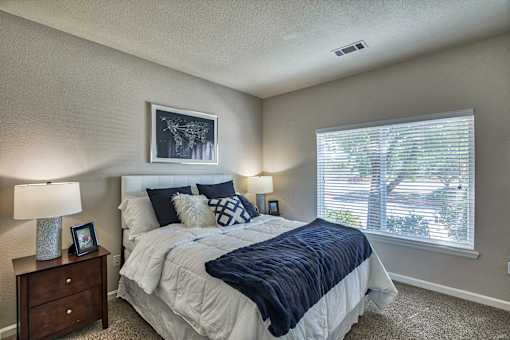 A bedroom with a large bed and a window with blinds.