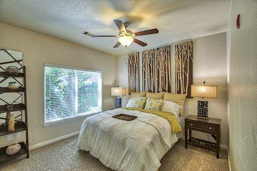 A bedroom with a bed, nightstand, and window.