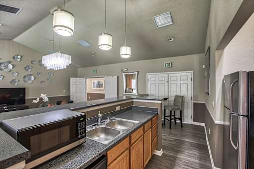 A kitchen with a black microwave, stainless steel refrigerator, and wooden cabinets.