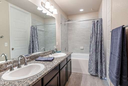 A bathroom with a sink, mirror, and shower.