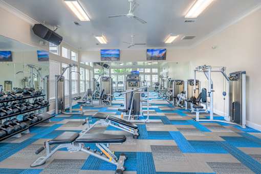 A gym with a variety of equipment including treadmills, weights, and exercise machines.