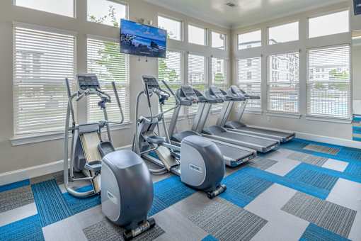 A gym with a row of treadmills and exercise bikes.