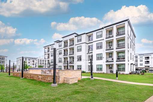 A large white apartment building with a grassy area in front.