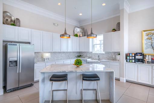 A kitchen with a marble island and two bar stools.