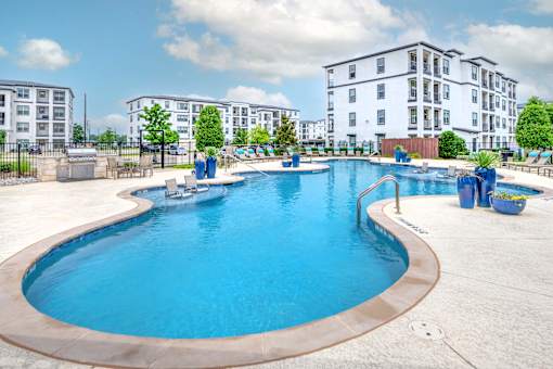 A large outdoor swimming pool with a slide and a building in the background.