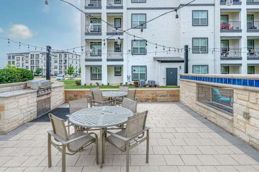 A patio with a table and chairs is in front of a building.
