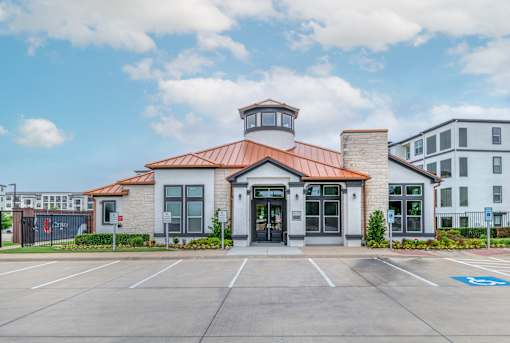 A building with a red roof and a parking lot in front.