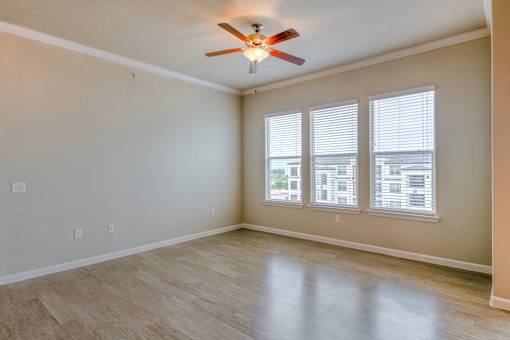 A room with a ceiling fan and a window with blinds.