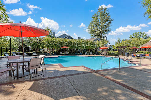 a swimming pool with tables and umbrellas next to it