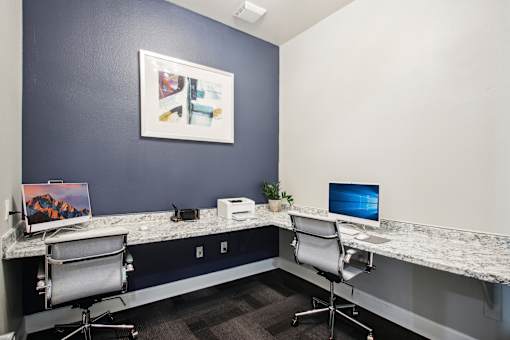 an office with two desks and two chairs and a computer