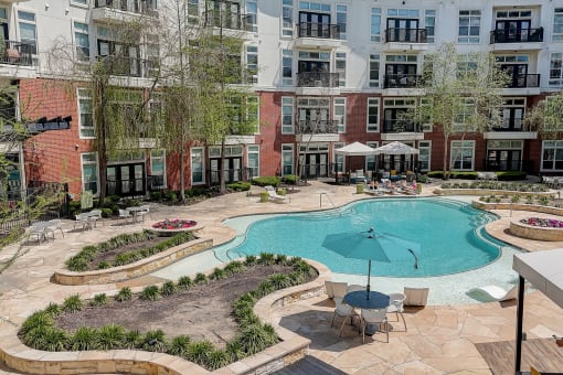 a swimming pool with an umbrella in front of an apartment building