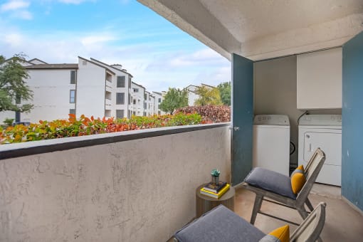 a balcony with two chairs and a table and a washing machine