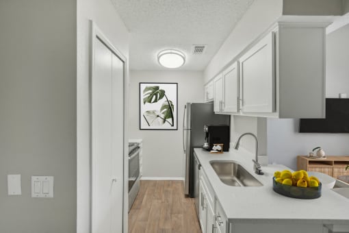 an open kitchen and living room with white cabinets and a white counter top