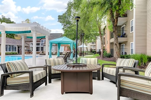 A patio with a table and chairs and a pool in the background.