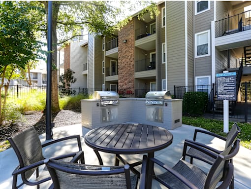 A patio with a table and chairs is surrounded by apartment buildings.