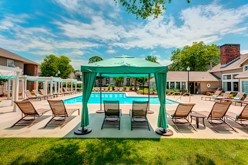 A pool area with a green canopy and lounge chairs.