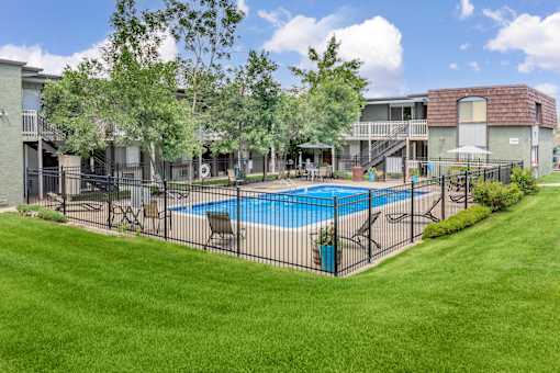 A pool surrounded by a black fence in a grassy area.