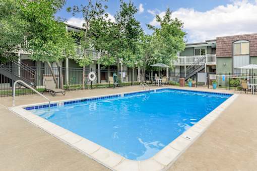 A large swimming pool surrounded by a fence and trees.