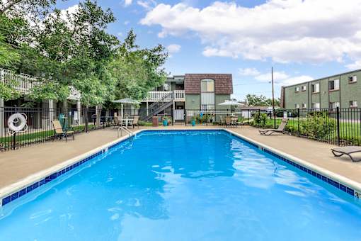 A swimming pool surrounded by a fence and trees.