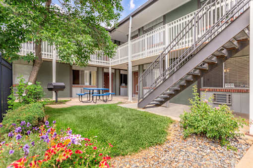 A patio with a table and chairs is surrounded by a garden.