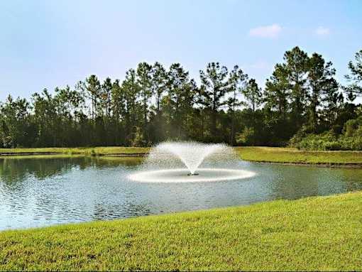 A fountain in the middle of a lake surrounded by trees.