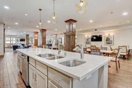 a large kitchen with an island and a dining room with tables and chairs