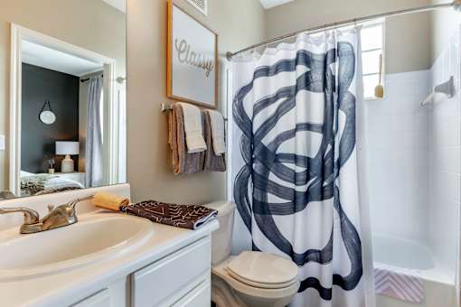 A bathroom with a white sink and a shower curtain with black lines.