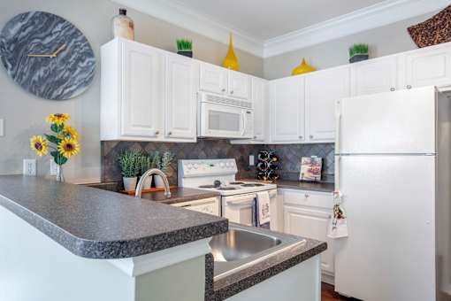 A kitchen with white cabinets and a marble countertop.