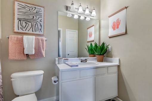 A bathroom with a white toilet, sink, and a pink towel hanging on the wall.