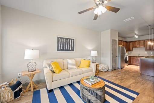 a living room with a ceiling fan and a blue and white striped rug
