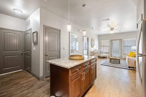 a kitchen with an island and a living room in the background