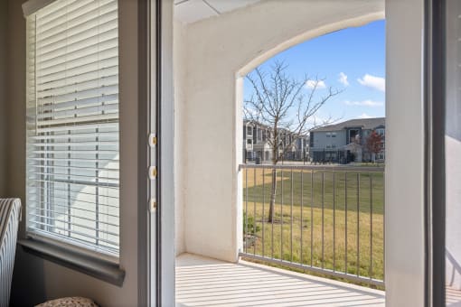 a patio with a view of a grassy field and houses in the background
