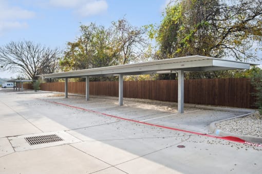 a covered parking lot with trees in the background