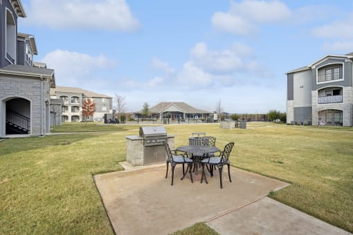 a patio with a table and chairs and a grill