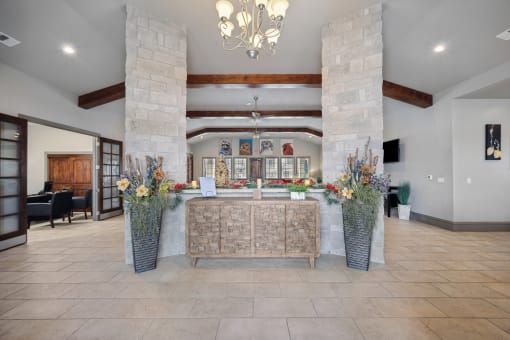 a lobby with a reception desk and large vases with flowers on the floor