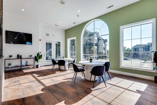 A room with a white table and chairs with a window in the background.