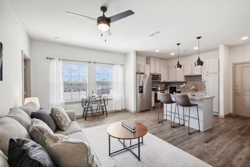 a living room with a couch and a table in front of a kitchen