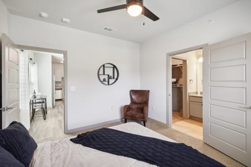 a bedroom with a large bed and a ceiling fan    and a bathroom