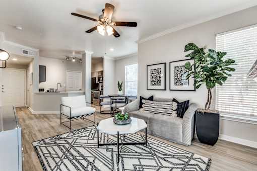 A living room with a white couch, a black and white rug, and a ceiling fan.