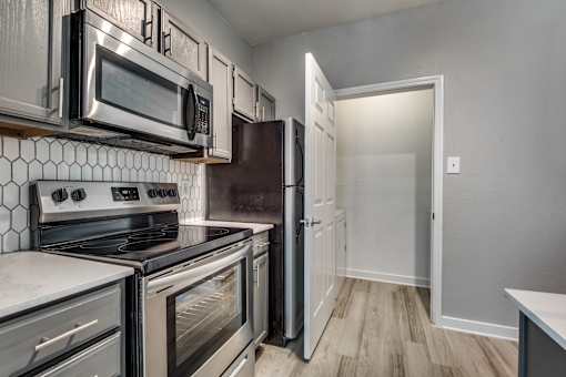 A kitchen with a white tile backsplash and stainless steel appliances.