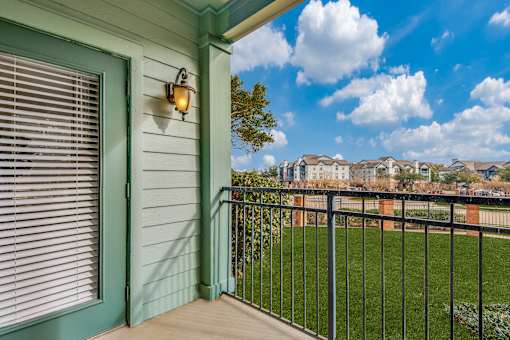 A balcony with a green door and a black railing.