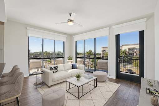 A well-lit, spacious living room with plank wood flooring and large windows.
