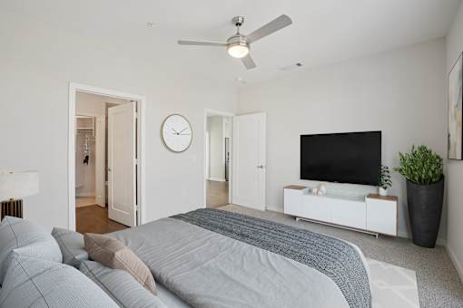 A spacious, modern bedroom accommodating a large bed and TV console.