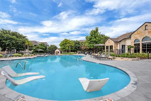 Wide view of the freeform pool with in-water loungers and surrounding sun deck.